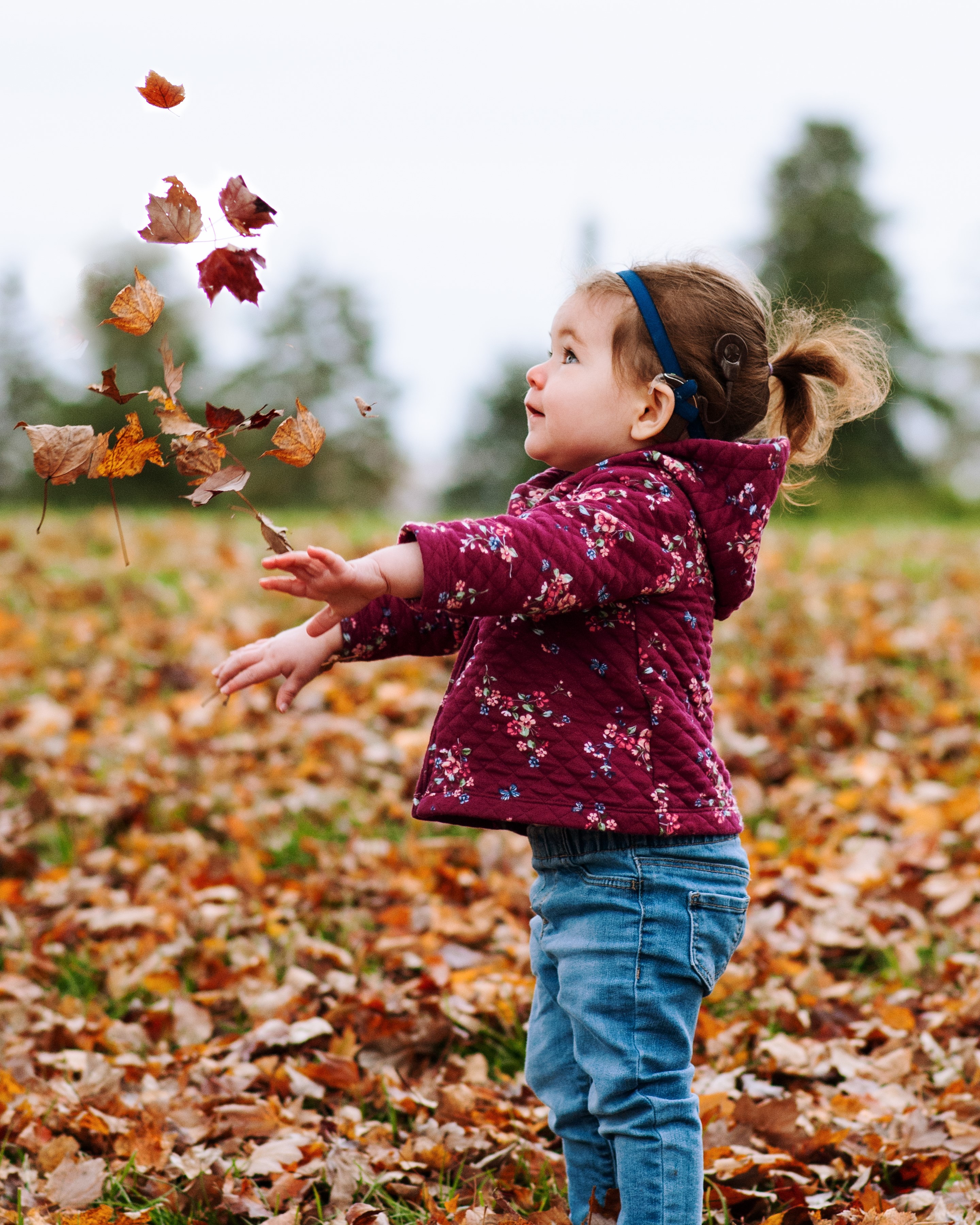 child, with bilateral sensorineural hearing loss, playing with leaves