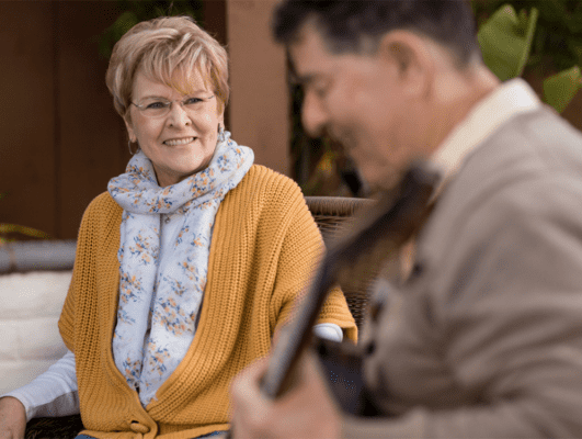 women listening to man playing the guitar