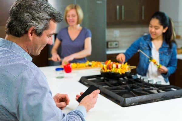 A man in his kitchen is on his phone learning about hearing therapy myths.