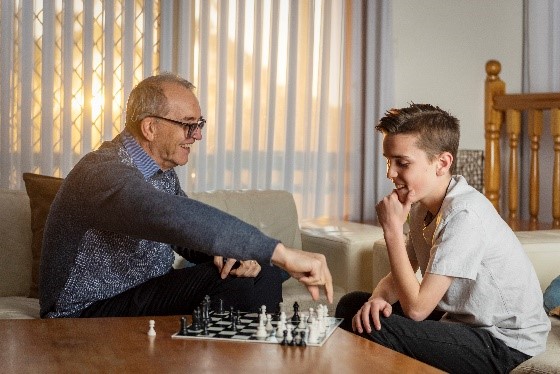 A grandfather and grandson play chess and demonstrate ways family can support with hearing therapy