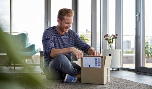 A man sits opening his package from the Cochlear Store.