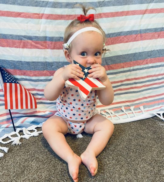A picture of Giada, who is holding an American Flag star, who was diagnosed with profound hearing loss.