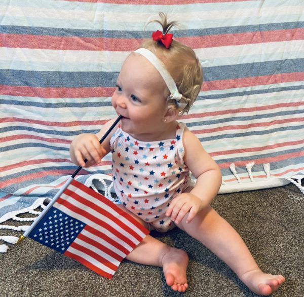 A picture of Giada, with a flag, who was diagnosed with profound hearing loss. 