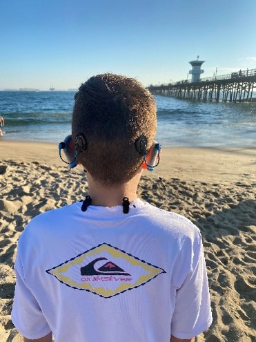 Evan, at the beach, showing his Nucleus 7's with his Aqua + accessory going back to school with a cochlear implant 