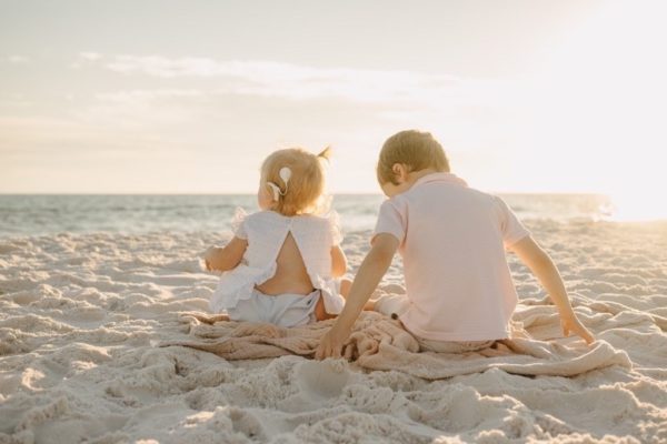 Henley, a girl with sensorineural hearing loss sitting next to hear brother on a beach. 