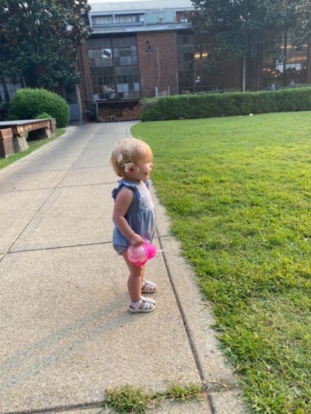 Henley, a girl with sensorineural hearing loss standing in front of a field of grass