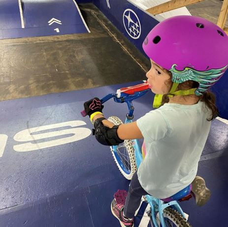 Gia, a girl with deteriorating hearing loss riding a BMX bike