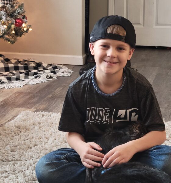 Carson, who failed his newborn hearing test, smiling with his pet cat. 