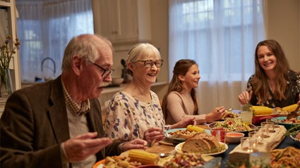 Upgrade sound processor, family gathering around table smiling and eating.