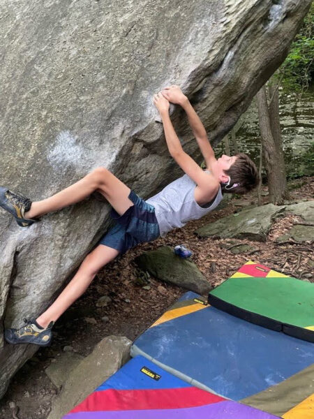 Grayson who has single sided hearing loss, climbing a rock 