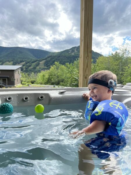 Better water resistance was an item on the Cochlear tech wish list. In this picture is a little boy in a hot tub smiling and wearing his Aqua+ accessory.