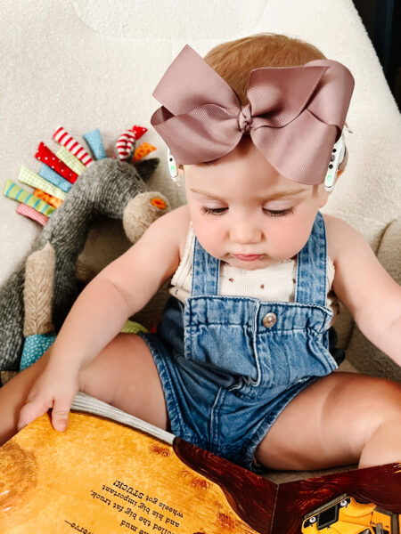 Ava, who has bilateral sensorineural hearing loss from MYO15A reading a book with her cochlear implants. 