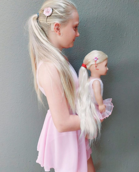 Cochlear's Achieve anything Global Summit ambassador, Tegan in her ballet outfit, showing her sound processor and her doll's matching outfit with wearing a sound processor