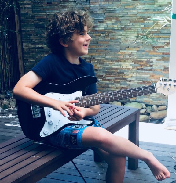 Felix whose family has emphasized music to help his speech and language skills, sitting with his guitar. 