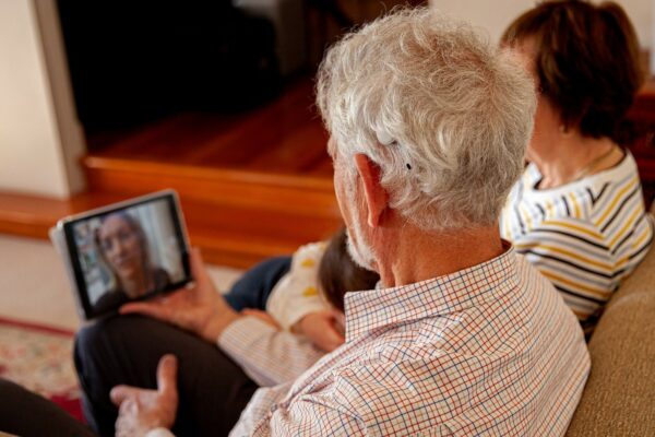Five myths about remote care; recipient talking on phone on a video call with audiologist.