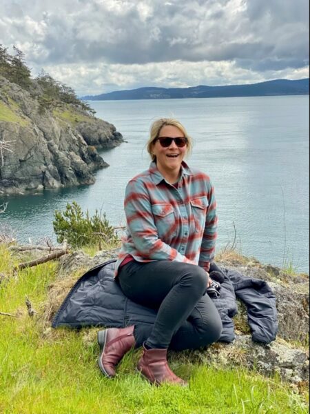 Lori, who has progressive hearing loss, posing by a large body of water. 