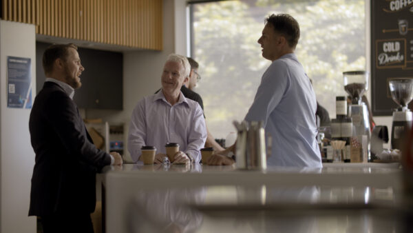 Bernie, a recipient who upgraded to a Nucleus 8 sound processor, talking with colleagues