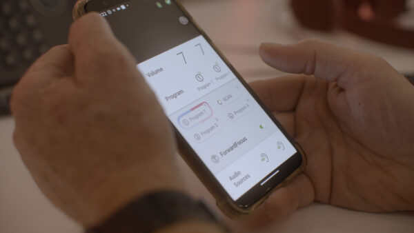 Bernie, a recipient who upgraded to a Nucleus 8 sound processor, using the Nucleus Smart App on his mobile phone