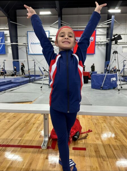 Sophia, whose family had no history of hearing loss, posing at a gymnastics gym. 