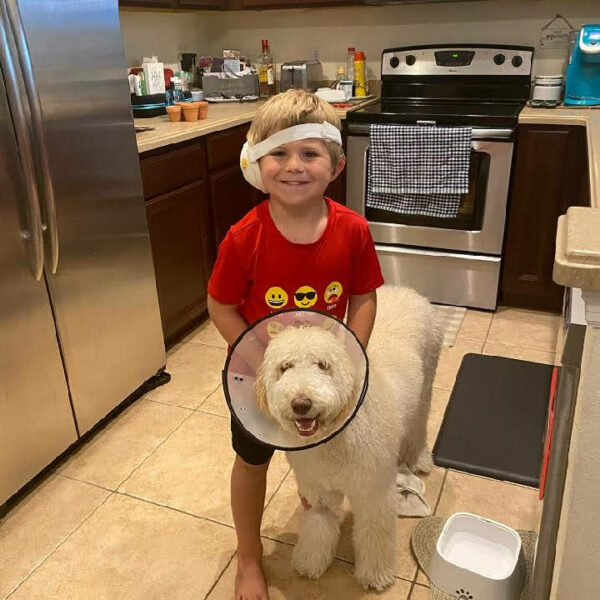 Jackson, a child with Usher syndrome and his dog posing after his cochlear implant surgery.