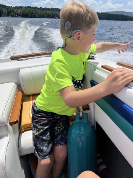 Jackson, a child with Usher syndrome enjoying riding on a boat, with his cochlear implants. 
