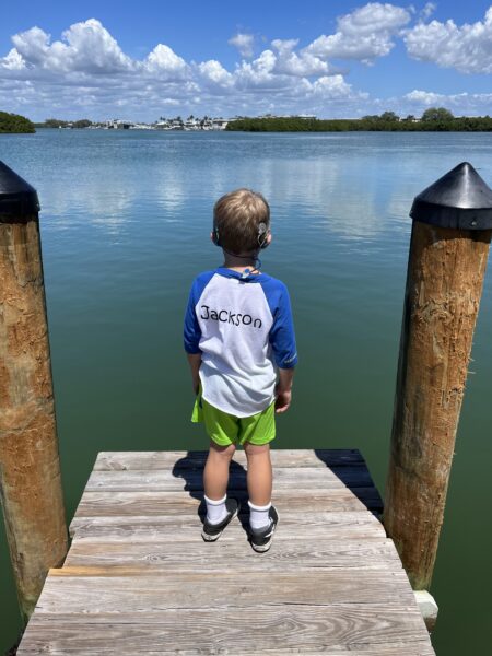 Jackson, a child with Usher syndrome, looking out at a lake with his bilateral cochlear implants. 