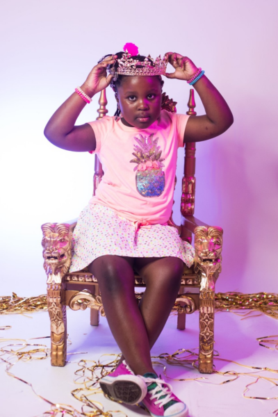 Grace, who was diagnosed with hearing loss from viral meningitis posing on a throne and placing a crown on her head. 