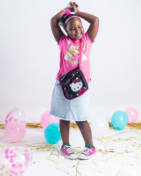 Grace who was diagnosed with hearing loss from viral meningitis, posing for a picture with her arms above her head, smiling. 