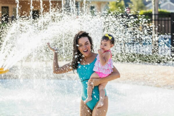 Mom and baby daughter splashing in a sprinkler; sound processor rated