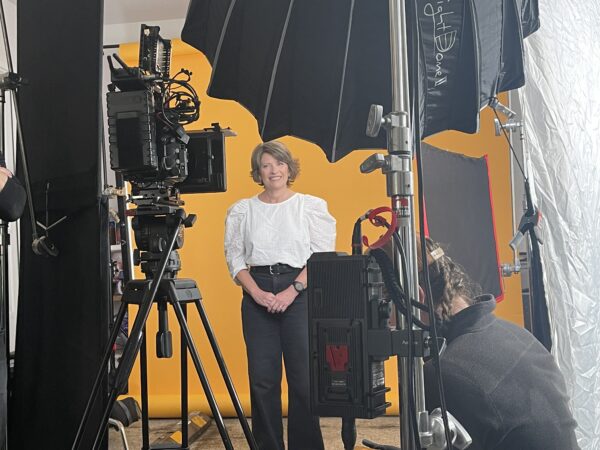Cochlear implant recipient Kathy, posing in front of a camera during her behind-the-scenes video shoot. 