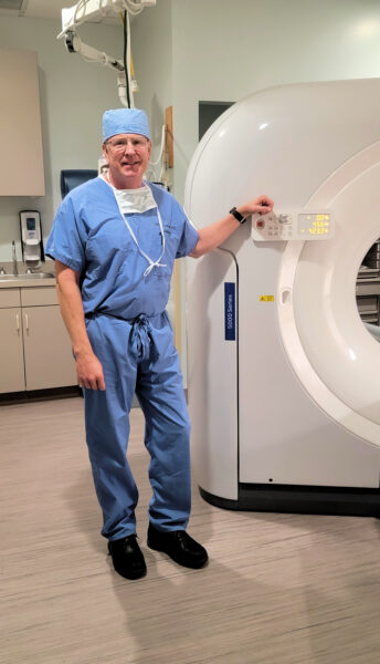 Eric, who has progressive sensorineural hearing loss posing at work in his scrubs for a photo. 