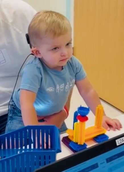 Gramm, a child with bilateral hearing loss pictured reacting to his cochlear implant activation appointment. 