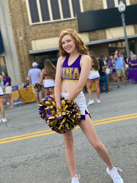 Born profoundly deaf in both ears, Riley poses for a photo during a parade in her college cheer uniform. 