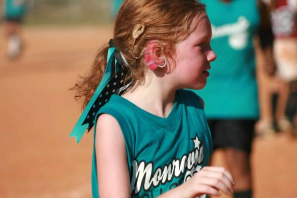 Born profoundly deaf in both ears, Riley is captured in an action shot playing a sport with her cochlear implant. 