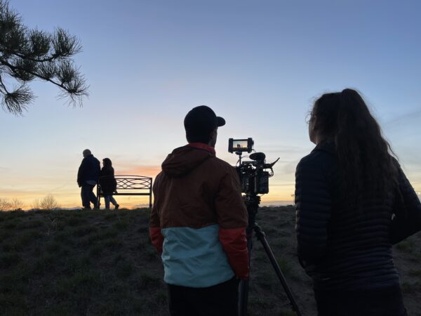 A photo of video equipment and a couple walking's silhouette at sunset during the behind-the-scenes video shoot. 