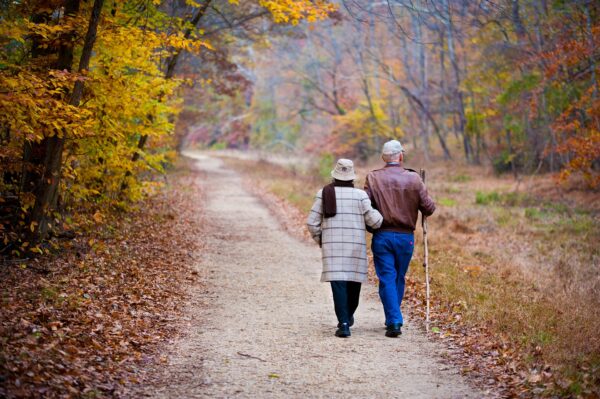 An older couple walks on a trail. 