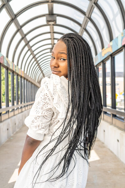 A picture of Kei-Che, a Hybrid Hearing Solution recipient posing on a bridge looking over her shoulder at the camera. 