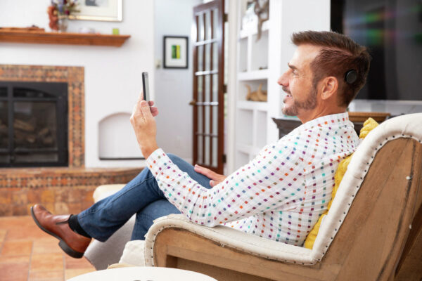 Man sitting in home with mobile phone; hearing practice exercises