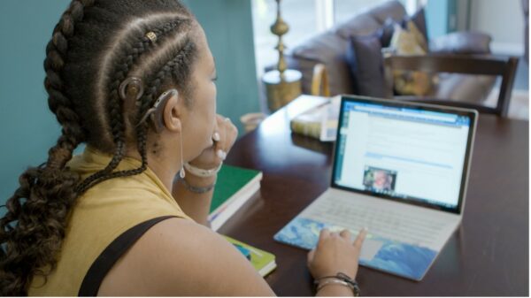 Recipient working from home using her laptop demonstrating hybrid working with hearing loss.
