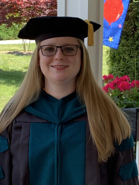 Laura, who has cochlear implants for Waardenburg syndrome, posing for a photo in her graduation cap and gown. 