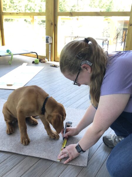 Laura, who has cochlear implants for Waardenburg syndrome, working on a home project with a puppy in front of her. 