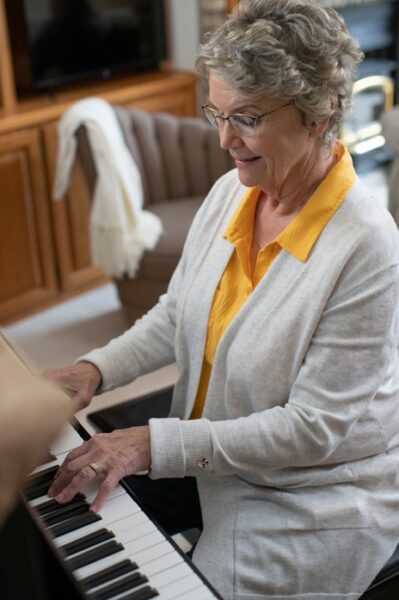 Recipient, Nancy, wearing her Nucleus 8 Sound Processors playing music on the piano