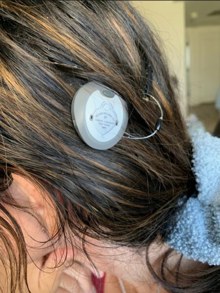 Shelby, who receives hearing clarity from Cochlear's Osia System, with a close-up picture of her Osia Sound Processor. 