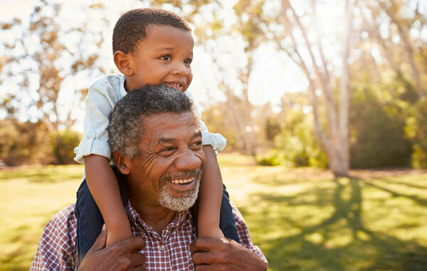 Recipient carrying boy on shoulders; learn more about your over 50 hearing screening checklist.
