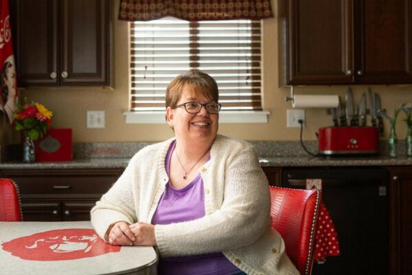 Michelle, smiling in her kitchen, demonstrating tips for managing two hearing devices.