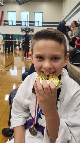 Parker, whose cochlear implant was an option for his single-sided deafness wearing a karate uniform and biting a medal between his teeth. 