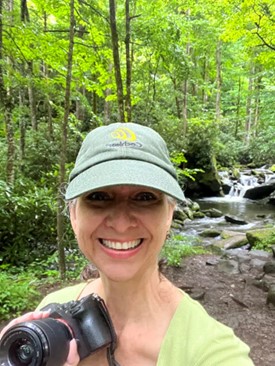 Kathleen is wearing a hat with her cochlear hearing device while taking photographs on a hike.