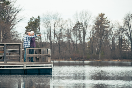 Scot, who uses the new Nucleus 8 Sound Processor technology, standing on a dock with his wife, pointing to something on the water. 