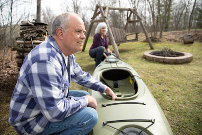 Scot, who uses the newest Nucleus 8 Sound Processor technology, pulling a canoe with his wife and staring into the distance. His cochlear implant is visible on his ear. 