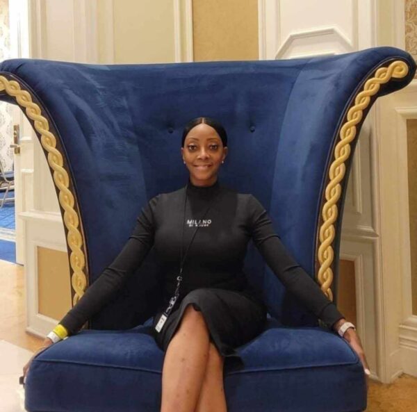 Chekesha, who has lived with hearing loss from addiction, shown smiling for a photo in a giant elegant blue chair. 